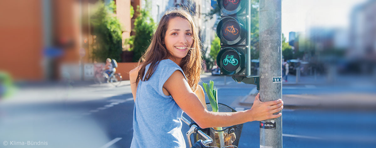 Frau auf Rad steht an einer Ampel