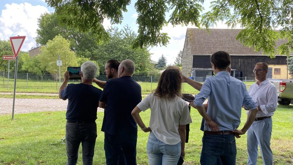 Teilnehmer*innen erkunden den Blick auf die Windkraftanlagen aus dem Dorf
