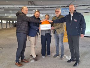 Die offizelle Einweihung des Parkahsues am Ryck. Vier Personen halten symbolisch Ihre hand auf einen großen orangenen Knopf. Davor befindet sich die Aufschrift: "Start frei für Sonnenstrom am Ryck.
