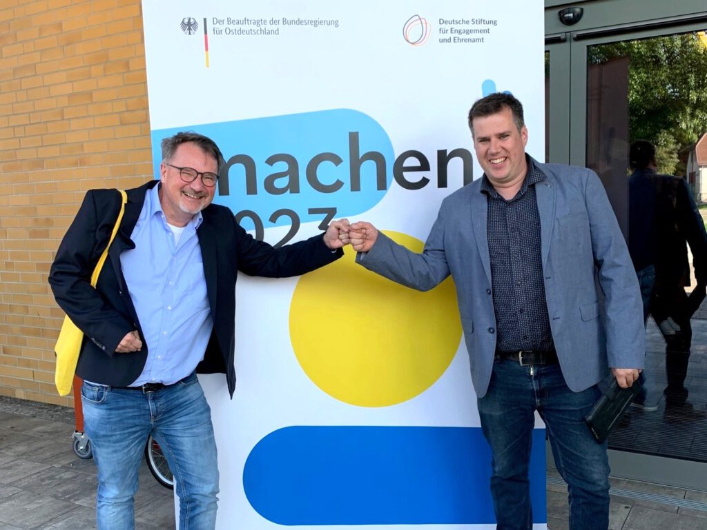 Zwei Männer geben sich freudig eine Ghetto-Faust vor einem Roll-up