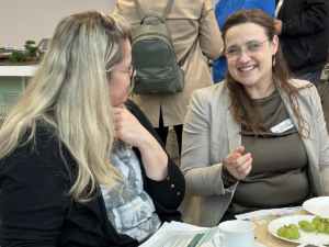 Stefanie Beitz im Gespräch mit einer Kommunalvertreterin. Stefanie Beitz lacht dabei fröhlich in die Richtung der Kommunalvertreterin