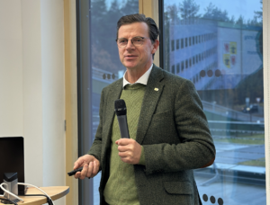 Axel Papendieck stellt die KfW-Förderprogramme für den kommunalen Klimaschutz vor. Er hält ein Mikrofon in der Hand