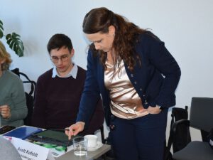 Ein sitzender Mann und eine stehende Frau im Gespräch vertieft.