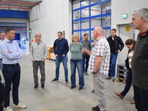 Eine Menschengruppe befindet sich in einer modernen Produktionshalle der Firma Weber Food Technology und hört einem in der Mitte stehendem Menschen zu.