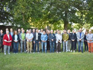 Gruppenfoto der Teilnehmenden einer Veranstaltung des Kommunalnetzwerks der Landesenergie- und Klimaschutzagentur Mecklenburg-Vorpommern auf einer Wiese.