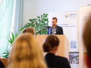 Referent hält einen Vortrag beim Kommunalnetzwerk der Landesenergie- und Klimaschutzagentur Mecklenburg-Vorpommern vor einem Fachpublikum.