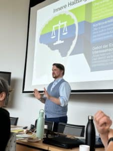 Ein Mann steht vor einer Präsentationswand und erklärt etwas